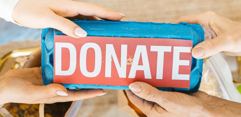 Hands exchanging a donation box filled with items, symbolizing giving and community support.
